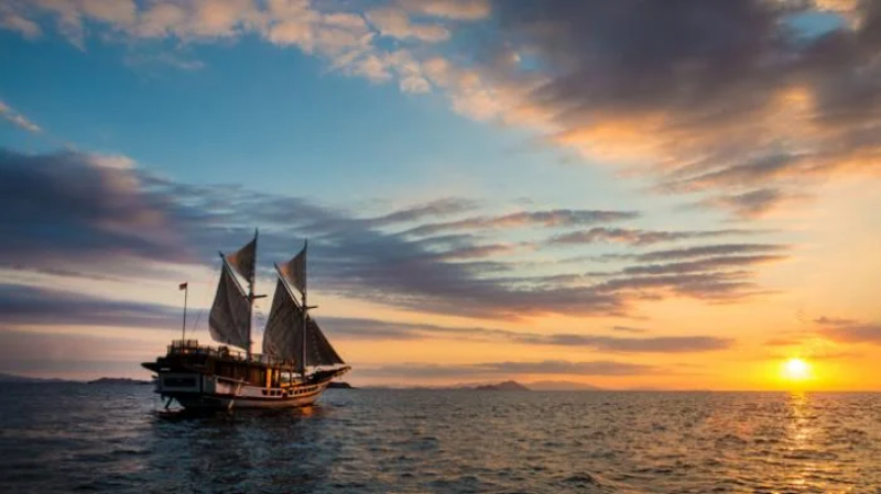 kapal pinisi berlayar saat sunset di laut makassar
